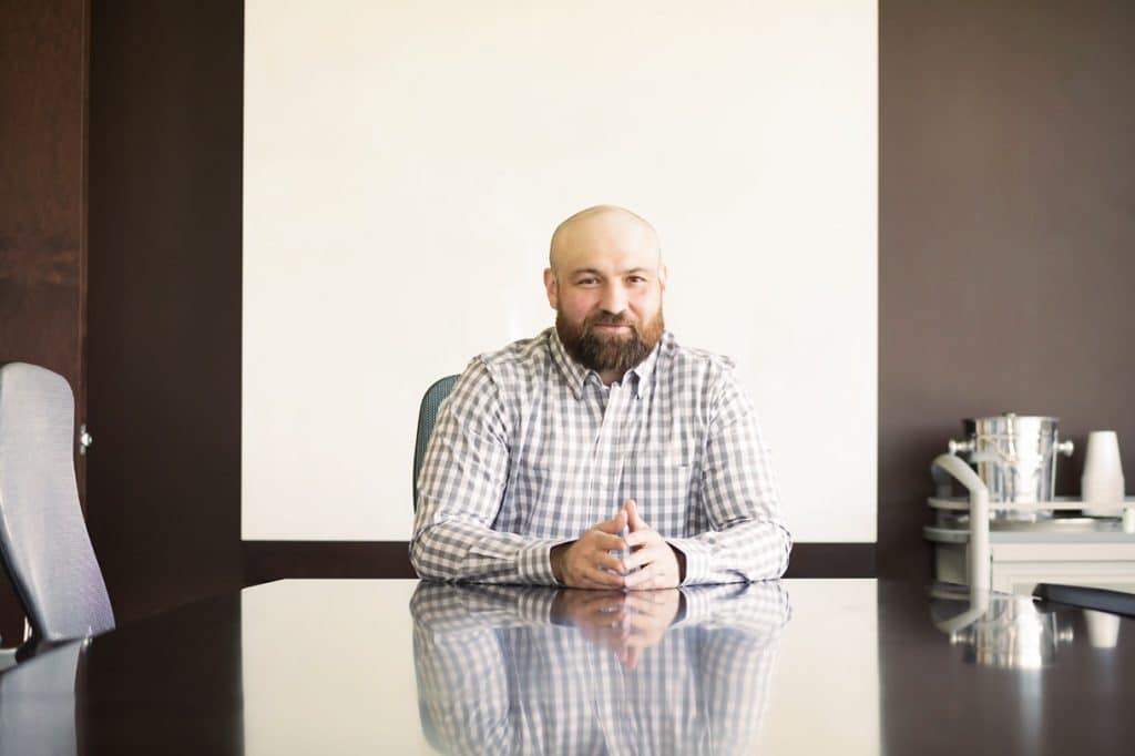 Kris Rivenburgh seated at a conference table and smiling.